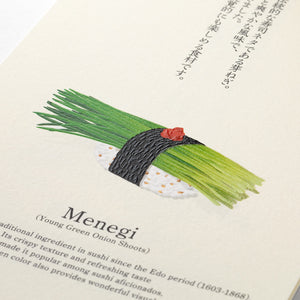 A close-up of a printed page featuring an illustration of a green onion shoot wrapped in black seaweed and topped with a small red garnish, placed on white rice. The page includes the word 'Menegi' and some descriptive text in English and Japanese.