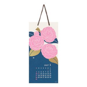 A hanging wall calendar page for January 2027 with three large pink flowers and blue leaves on an off-white background, plus a dark blue lower section with a small calendar grid. The calendar has brown hanging straps and is shown against a plain white background.