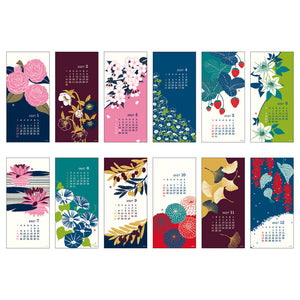 A set of twelve vertical calendar pages or bookmarks featuring different floral and botanical illustrations, arranged in two rows on a plain white background. Each page includes a small monthly calendar grid and decorative artwork such as pink flowers, strawberries, lilies, water lilies, ginkgo leaves, and red berries.