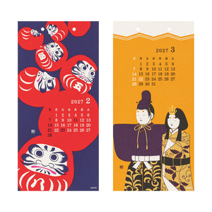 Two Japanese wall calendars shown side by side on a white background. The left calendar features red Daruma doll illustrations on a dark blue background with a February 2027 calendar grid.