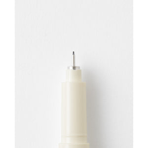 Close-up of a cream-colored marker or pen tip with a silver metal needle, set against a clean white background.