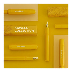Yellow Kaweco Collection fountain pen components and matching yellow packaging arranged in a flat-lay composition on a yellow background, with one pen nib and cap section shown vertically and the text 'KAWECO COLLECTION' visible on the box.