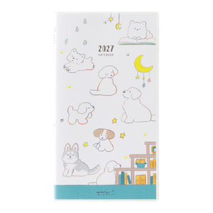 A 2027 daily planner with a cute, minimalist dog-themed illustration on a white cover, featuring pastel-colored drawings of dogs, a bunny, a cat, stars, moons, and a teal band at the bottom.
