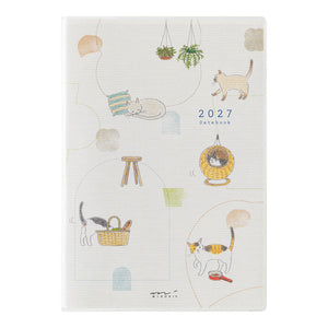 A 2027 daily planner notebook with a white textured cover decorated with whimsical cat illustrations and pastel doodles, shown against a plain white background.
