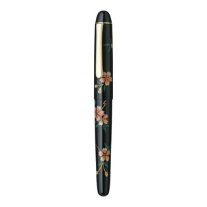A black fountain pen with a glossy finish, decorated with hand-painted cherry blossom flowers in pink, peach, and green, and accented with gold trim and a gold clip.