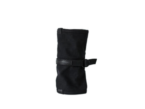 A black canvas wrist strap tool roll with a black leather strap and buckle, standing upright on a white surface against a white background. nomado store