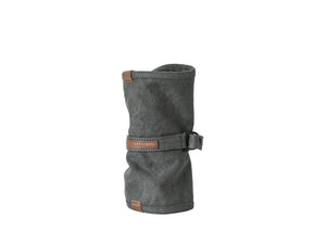 A dark gray canvas sleeve or pouch with brown leather trim and a strap closure, standing upright on a clean white studio background. nomado store