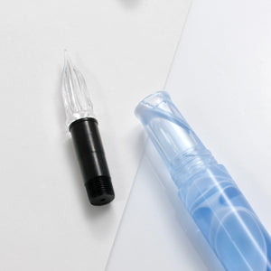 A close-up of a pen's nib and cartridge components on a clean white background. The nib is black with a clear ribbed tip, and the translucent blue cartridge is partially visible.