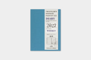 A 2027 weekly traveler's notebook by Traveler's Company, featuring a slate blue cover with a white vertical panel detailing the text and year.