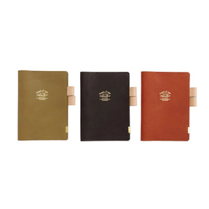 Three hardcover notebooks in olive green, black, and terracotta red, arranged side by side on a clean white background. Each notebook features a tan leather strap closure and a gold-embossed logo on the front cover.