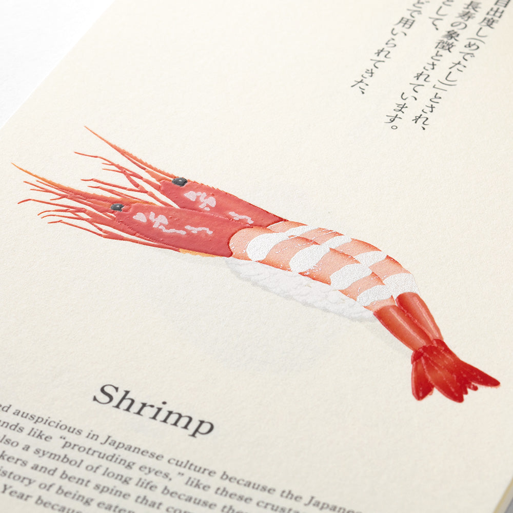 A close-up of a printed page featuring an illustration of a shrimp on a beige background with black text and Japanese characters.