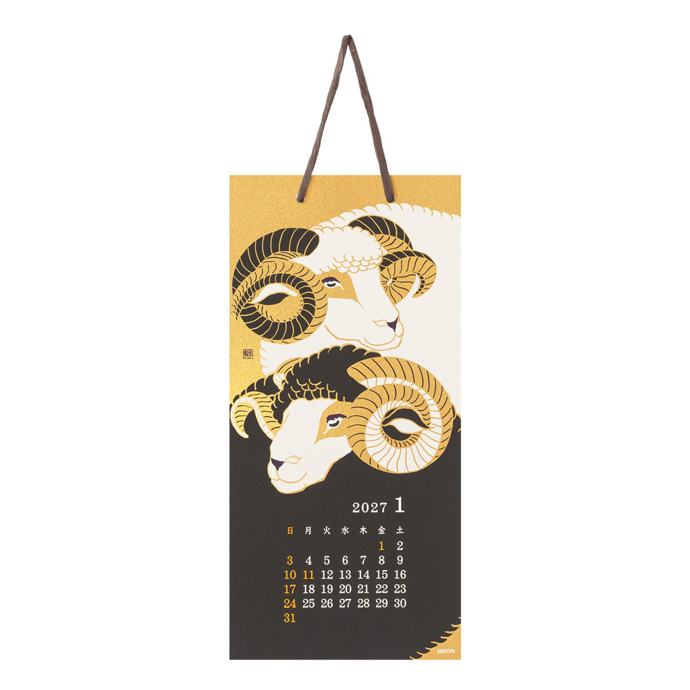 A hanging 2027 January calendar page featuring stylized ram illustrations in gold, black, and cream, with a dark brown hanging loop at the top.