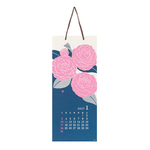 A hanging wall calendar page with a dark blue lower section, pink floral illustration at the top, and a small 2027 January calendar grid near the bottom. The calendar has a cream upper section and a brown hanging loop.