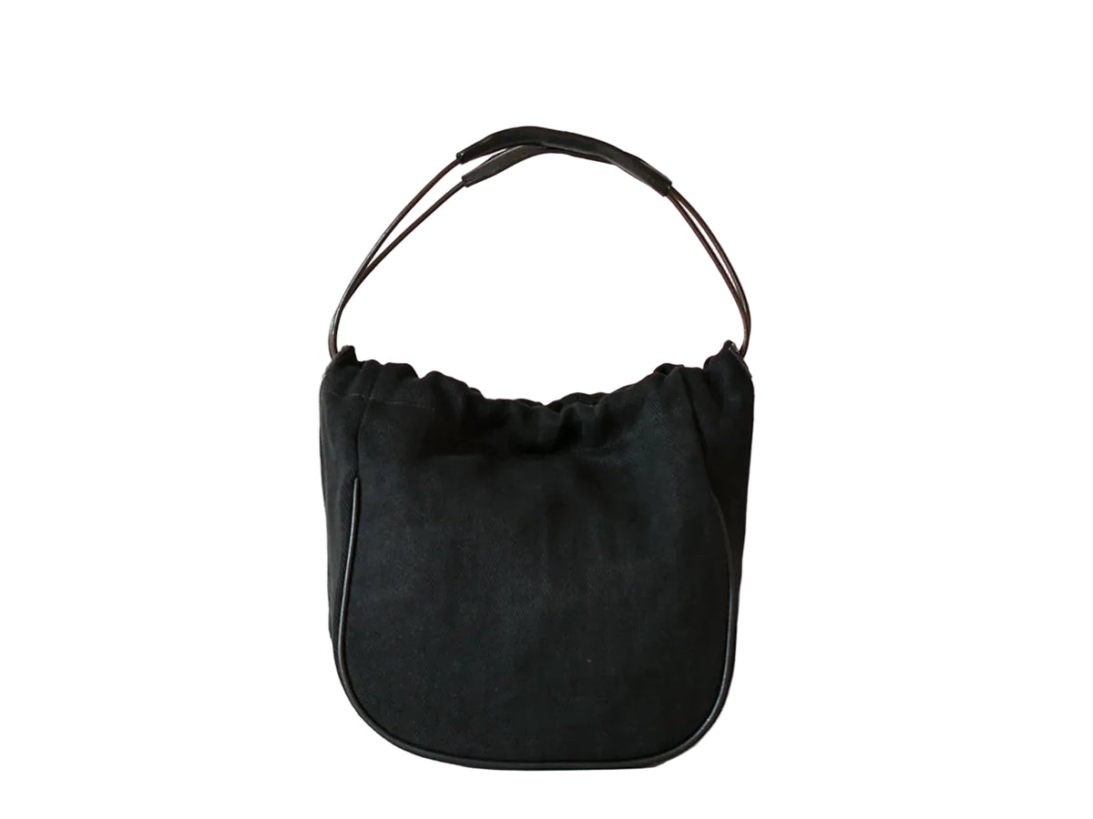 A black suede crescent-shaped shoulder bag with a thin black leather top handle, photographed against a clean white background.