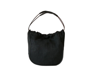 A black suede crescent-shaped shoulder bag with a thin black leather top handle, photographed against a clean white background.