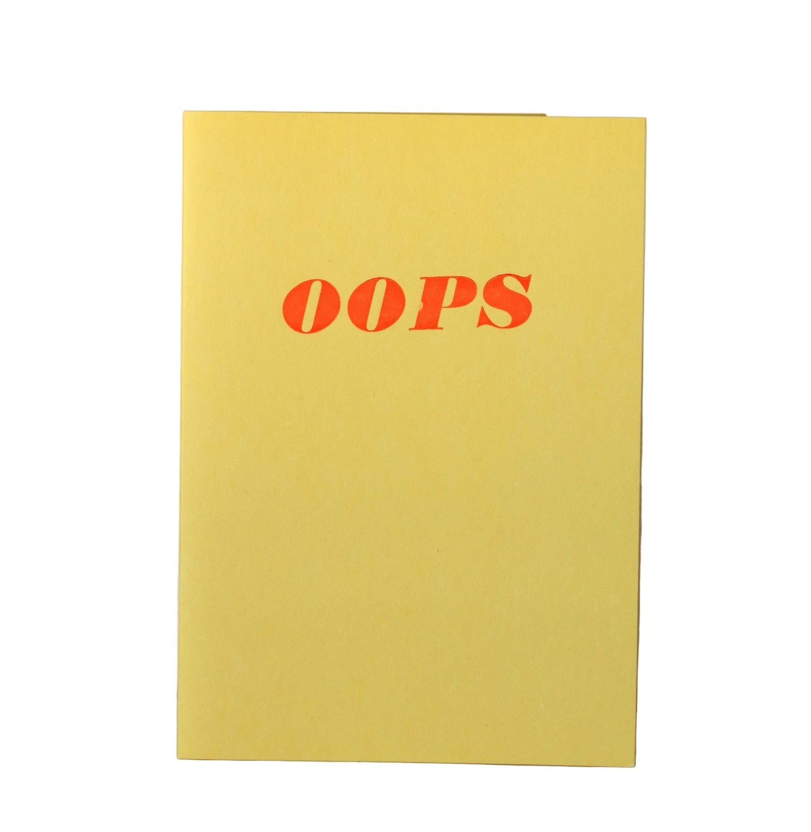 A yellow greeting card with the word 'OOPS' printed in red across the top center, standing upright against a plain off-white background.