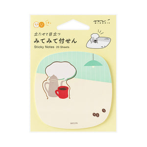 MIDORI brand sticky notes in a hanging card pack, featuring a cute illustration of a coffee table scene with a teapot, red mug, hanging lamp, and coffee beans on a pale yellow background.