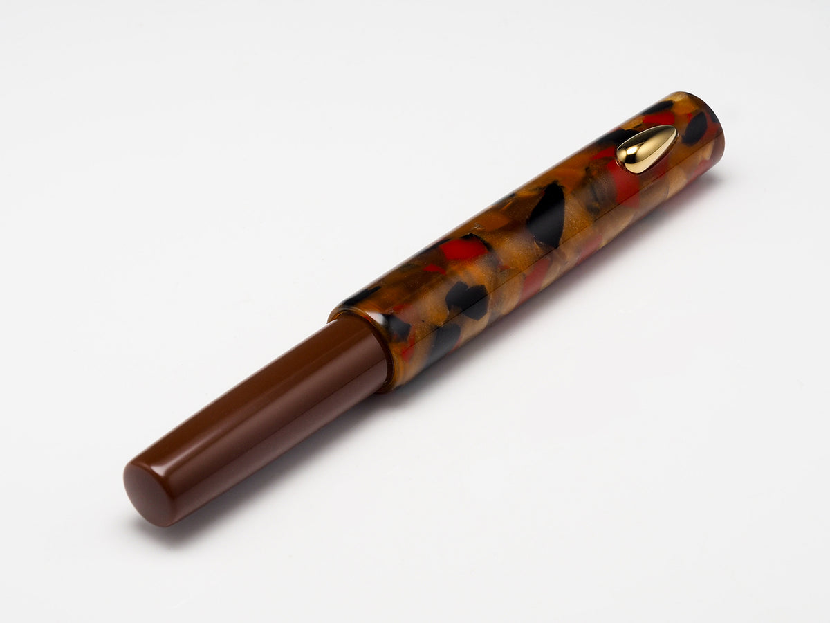 A tortoiseshell pen with a glossy brown barrel, black and red mottled pattern, and a gold clip, shown on a clean white background.