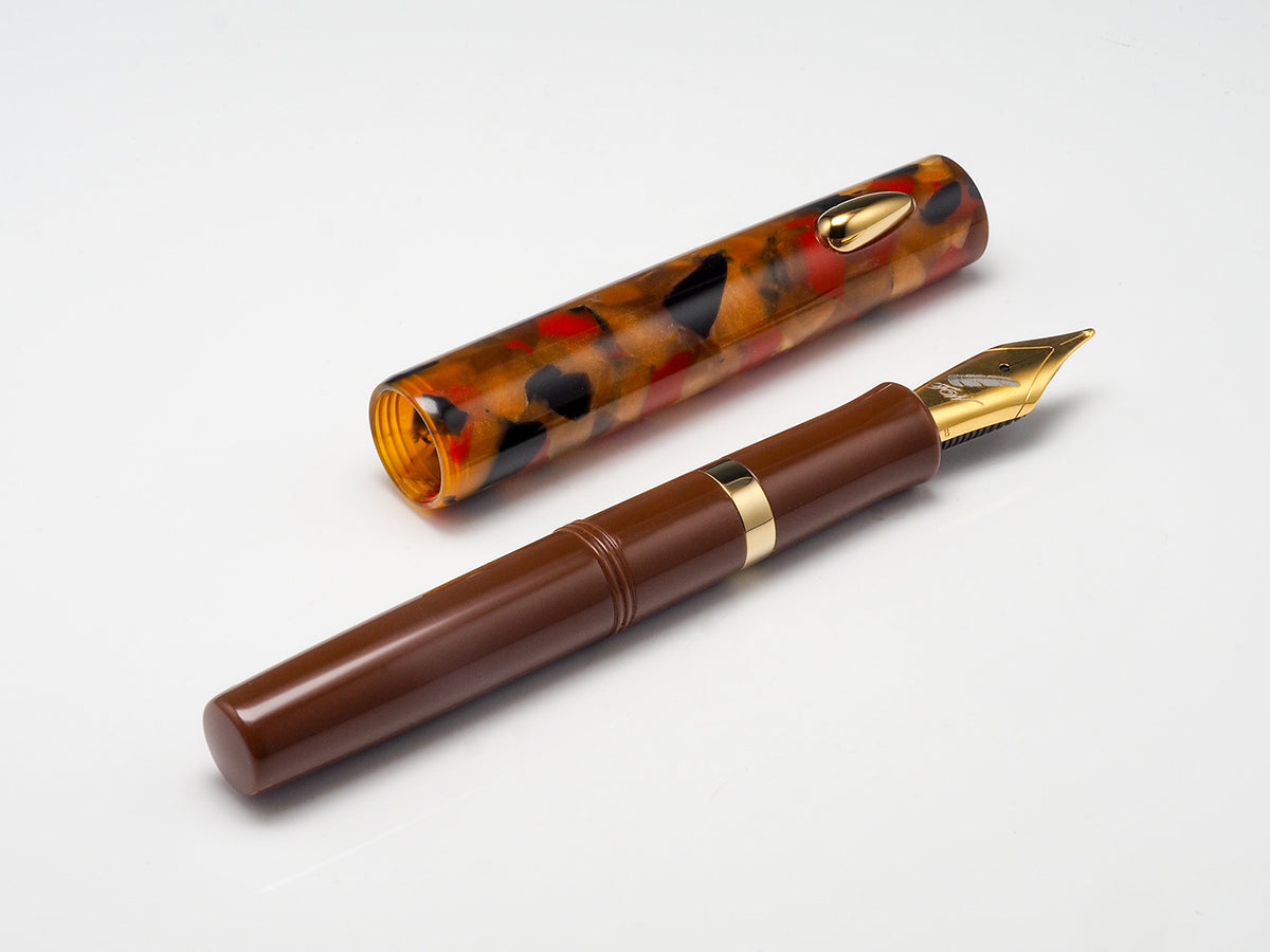 A brown fountain pen with a gold nib and trim, shown next to its matching tortoiseshell-patterned cap on a clean white background.