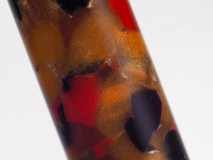 Close-up of a cylindrical product with a marbled, textured pattern of amber brown, orange, red, and black on a white background.