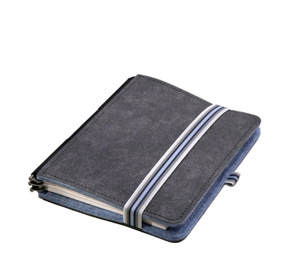A dark blue fabric notebook cover with two white diagonal stripes, shown closed on a light beige background with soft shadows.