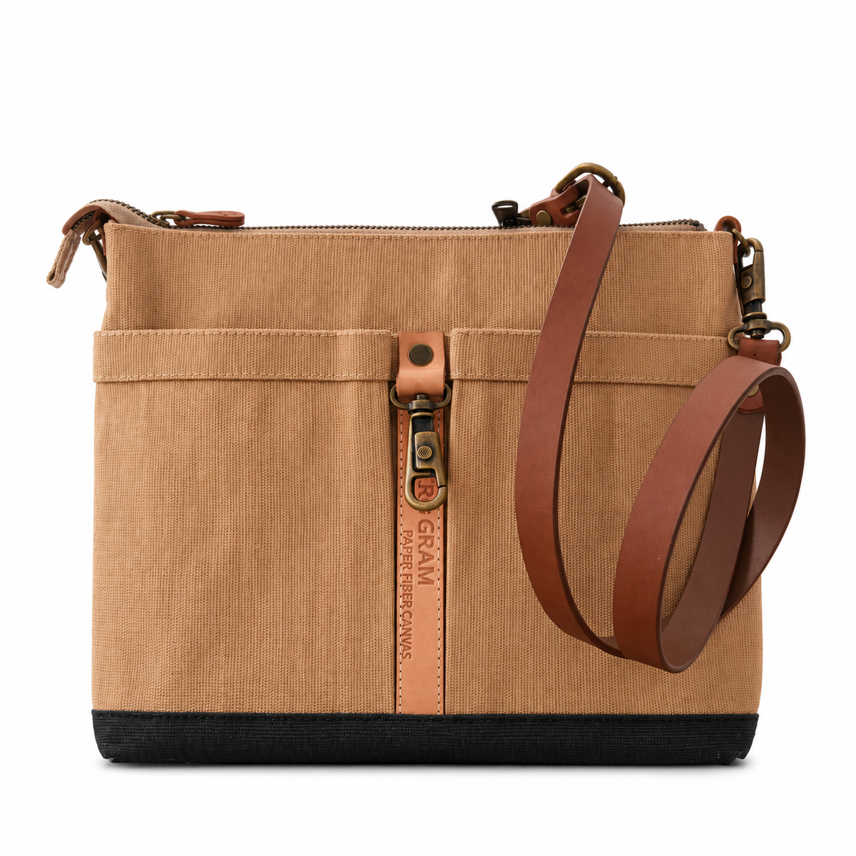 A structured canvas shoulder bag in tan with brown leather straps and a black base, featuring a vertical zippered pocket 