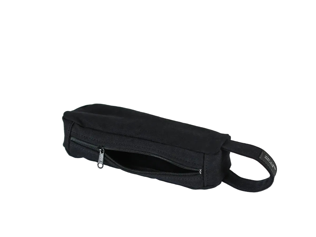A black canvas waist bag with a zippered front pocket and a black webbing strap nomado store.