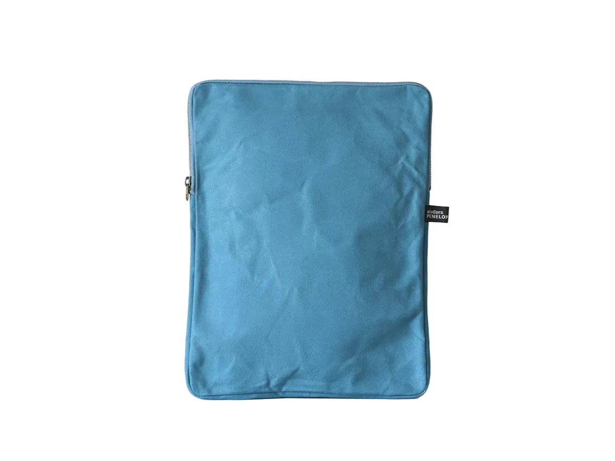 A blue fabric sleeve or pouch with rounded corners, standing upright against a plain off-white background. A small black fabric tag is visible on the right side.