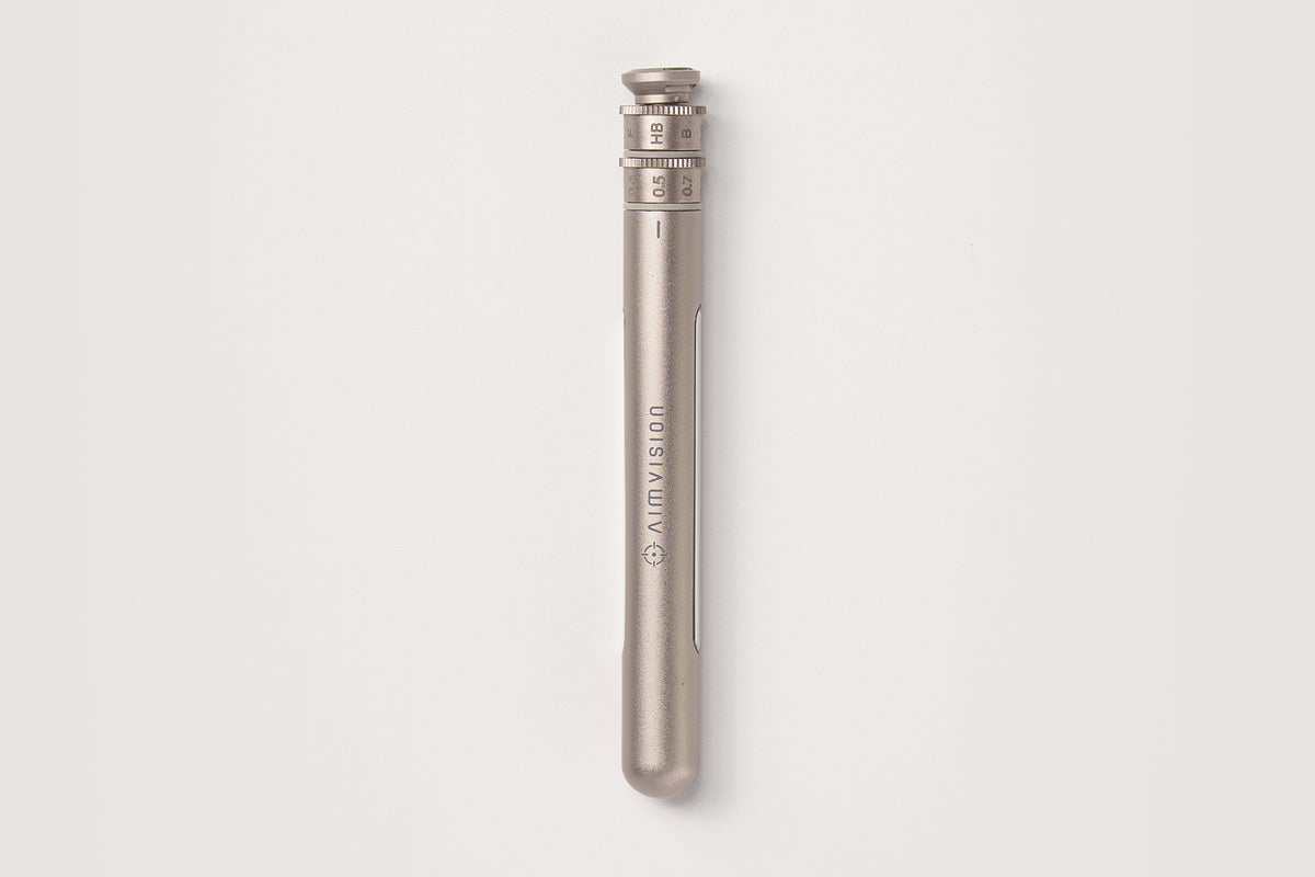 A sleek, metallic titanium gold pen with engraved branding and a textured top cap, shown vertically against a clean, light gray background.