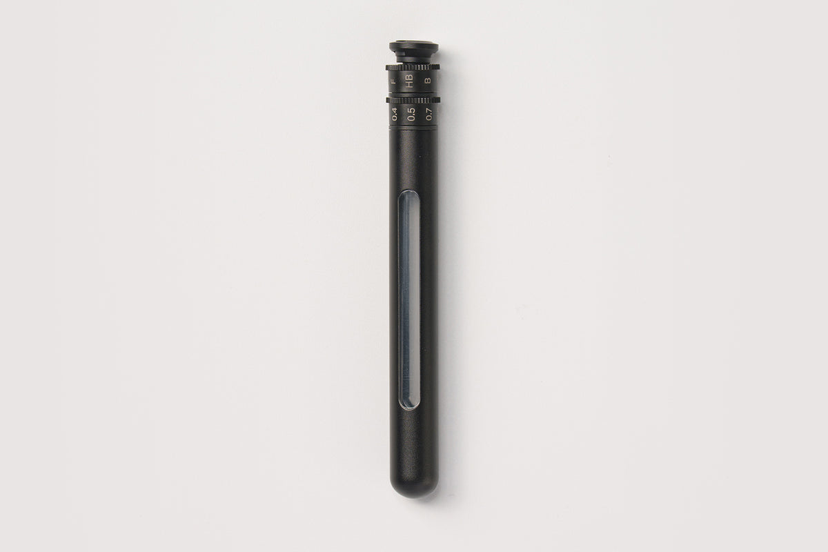 A sleek, matte black cylindrical device with a transparent vertical window showing a blue-gray interior, set against a solid off-white background.