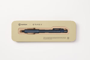 A KAYOU+ ORVO II ballpoint pen in a dark blue-gray color, presented inside its beige cardboard packaging with a clear window.