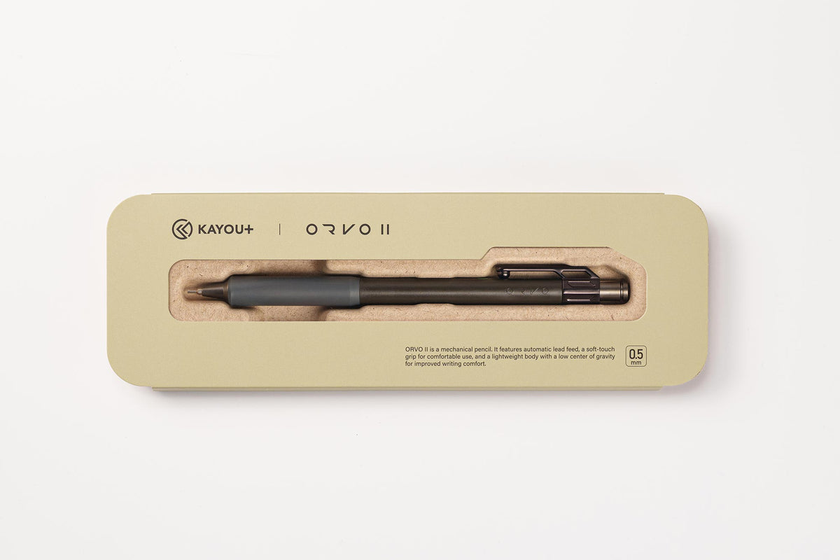 A KAYOU+ ORVO II ballpoint pen in a sleek rectangular beige metal case with a clear window, shown on a clean white background.