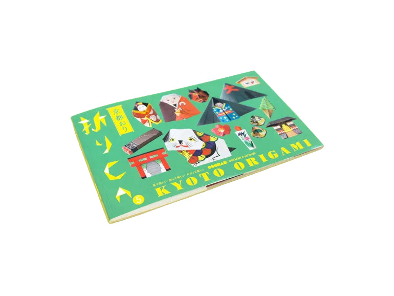 A book titled 'Kyoto Origami' with a bright green cover featuring colorful illustrations of Japanese origami crafts, photographed on a solid pale yellow background. By Cochae
