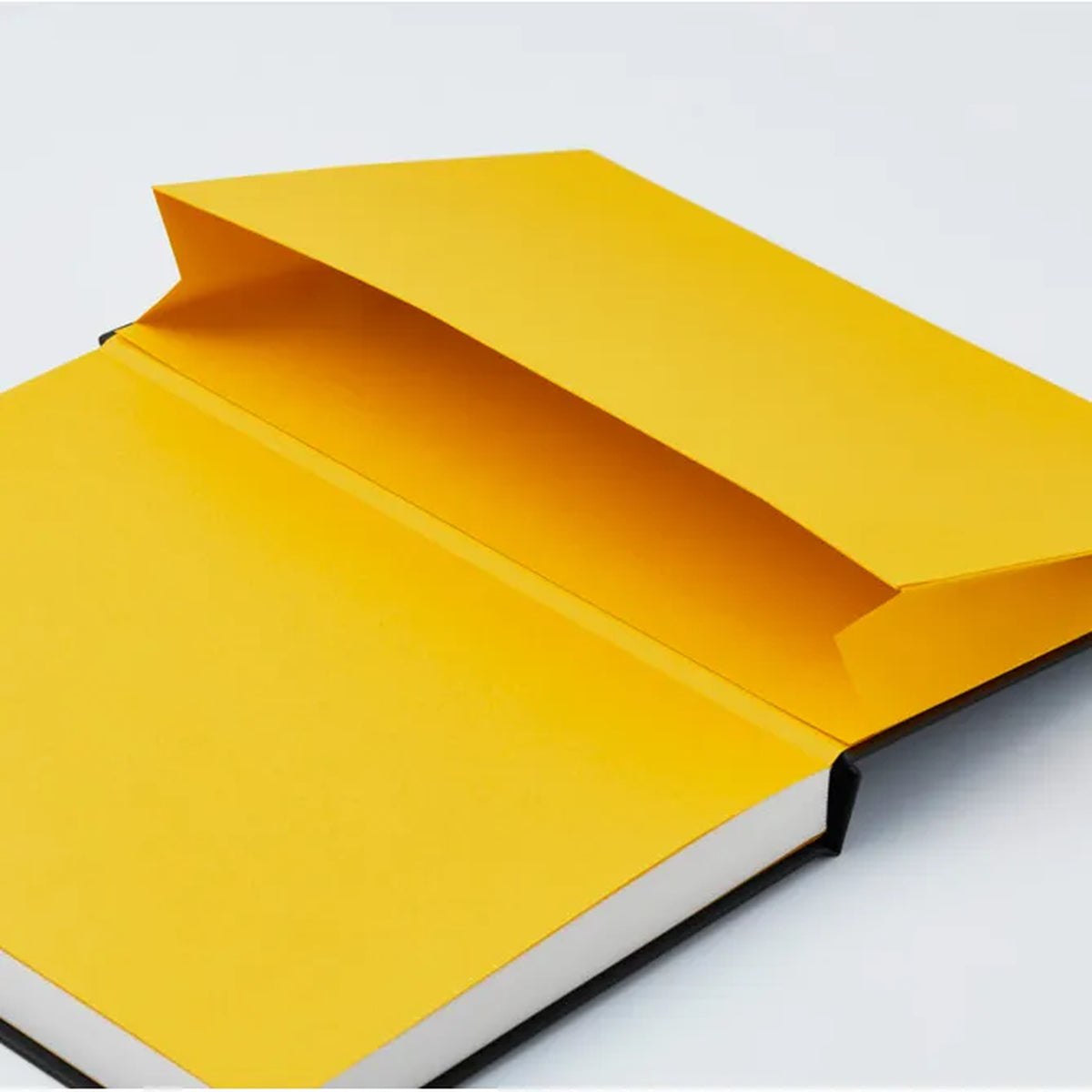 A hardcover notebook or journal shown open at an angle, with a bright yellow cover and white page edges visible against a clean white background.