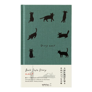 A 2027 daily diary with a textured teal-green cover decorated with black cat silhouettes, featuring a cream-colored lower third with English and Japanese text and a small kitten illustration.