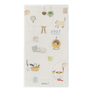 A 2027 daily planner notebook with a cream-colored cover decorated with cute cat illustrations and small doodles, shown against a plain white background.