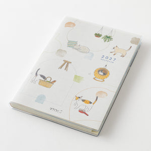 A 2027 daily planner with a white cover decorated with cute, minimalist cat illustrations in soft pastel colors, shown on a clean white background.