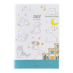 A 2027 daily planner dated '2027 DATEBOOK' on a white cover decorated with cute cartoon dog illustrations, a yellow crescent moon, stars, and a teal band at the bottom.