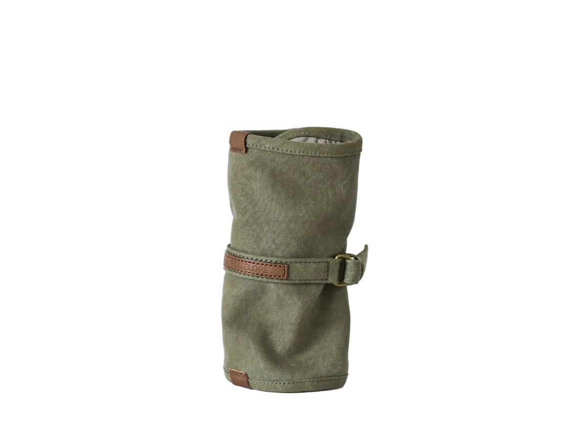 An olive green canvas roll-top pouch with brown leather strap and buckle closure, shown on a clean white background. nomado store
