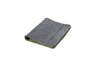 A closed gray suede or microfiber planner or notebook cover with a thin elastic band closure, resting on a light gray surface.